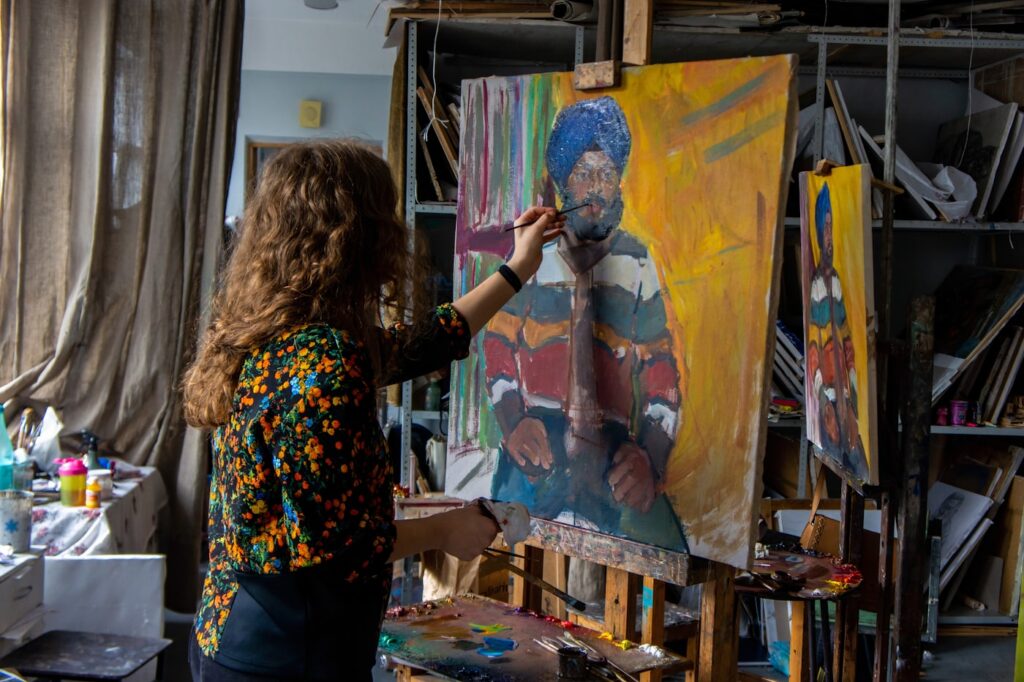 Woman painting a colorful portrait on canvas in her art studio