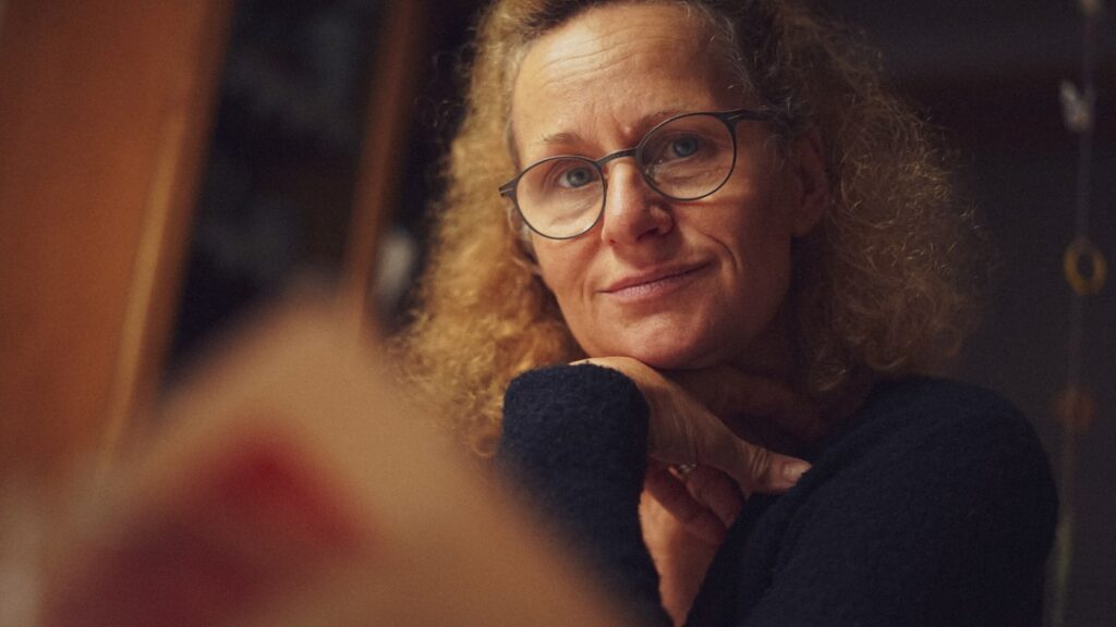 Woman in her sixties sitting thoughtfully, chin resting on her hand, reflecting on meaning and purpose after retirement